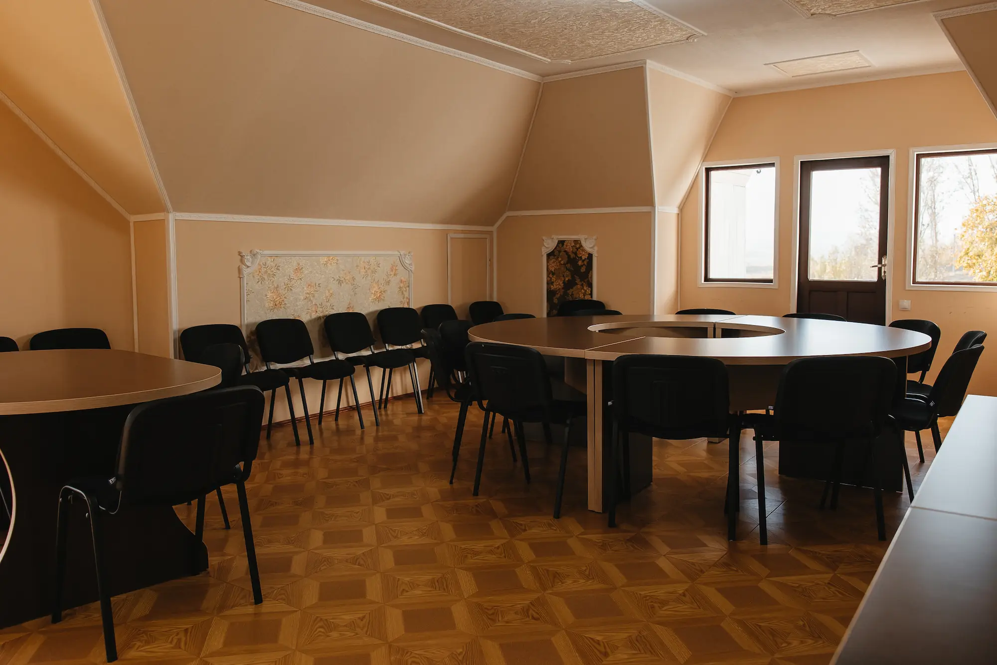 Sala de conferințe pregătită pentru o întâlnire de lucru, cu masă lungă, scaune aliniate și ecran pentru prezentări